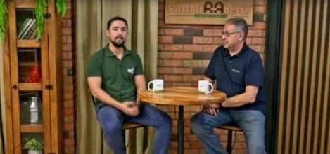 Dois homens sentados conversando sobre capacitação no campo. No fundo, há o cenário do Porteira Aberta Empreender, programa do Canal Rural